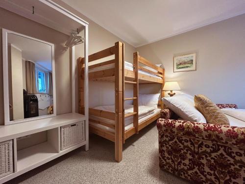 a bedroom with bunk beds with a mirror and a couch at Villa Aigner in Achenkirch