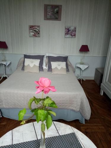 - une chambre avec un lit avec une fleur rose dans un vase dans l'établissement Gite Le Chalet, à Saint-Laurent-des-Vignes