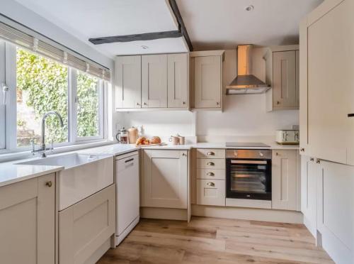 Darla Cottage في ثورنتون دالي: مطبخ بخزائن بيضاء ومغسلة ونافذة