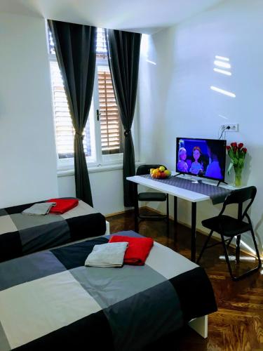 a room with two beds and a laptop computer on a desk at Pula-Center Apartments and Rooms in Pula