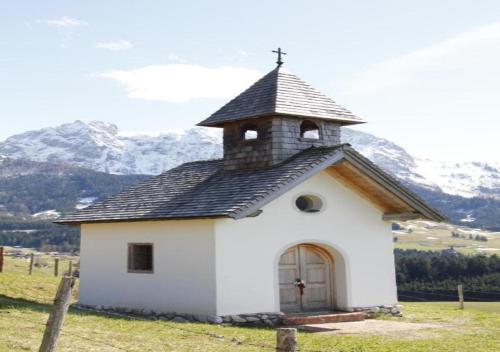 a small white church with a cross on the roof at ZIRBENHütte in Abtenau