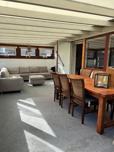 a patio with a wooden table and chairs and a couch at Dejlig og hyggelig hus i Thyborøn in Thyborøn