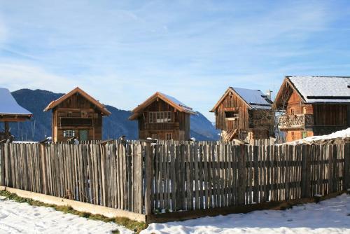 a fence in front of a wooden house in the snow at ZIRBENHütte in Abtenau