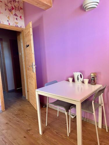 une table et des chaises dans une pièce dotée d'un mur violet dans l'établissement Chambre privée au pied des pistes - Chambre chez l'habitant - ChaletNelda com, à Lamoura