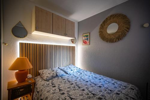 - une chambre avec un lit, une lampe et un miroir dans l'établissement L'Esprit Bohème - Terrasse - Proche camp naturiste, au Cap d'Agde