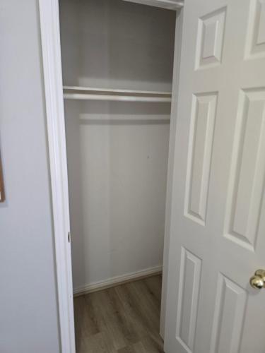 an empty closet with a white door and wooden floors at Fresh Crash Pads 4 in Houston