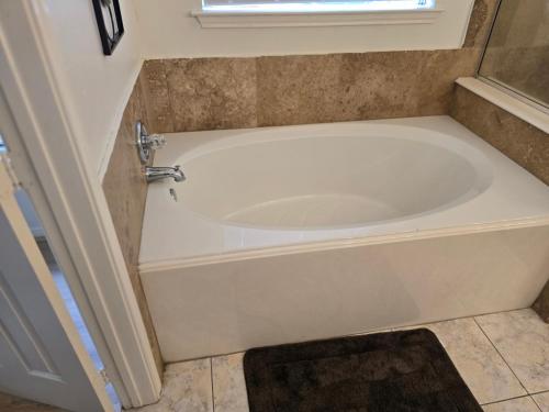 a white bath tub in a bathroom with a window at Fresh Crash Pads 4 in Houston