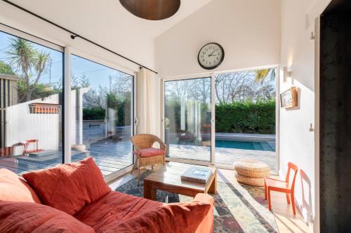 un salon avec un canapé et une horloge au mur dans l'établissement Magnifique maison basque avec piscine 8 pers- Biarritz, à Biarritz