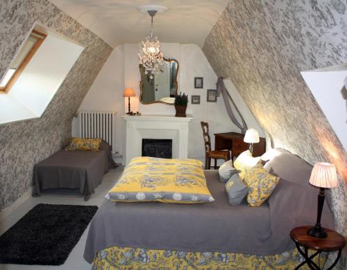 a bedroom with two beds and a fireplace at Logis Les Remparts in Bayeux