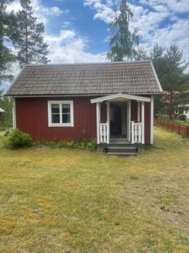 a red house with a white door in a yard at Stuga i Solvarbo, Dalarna in Gustafs