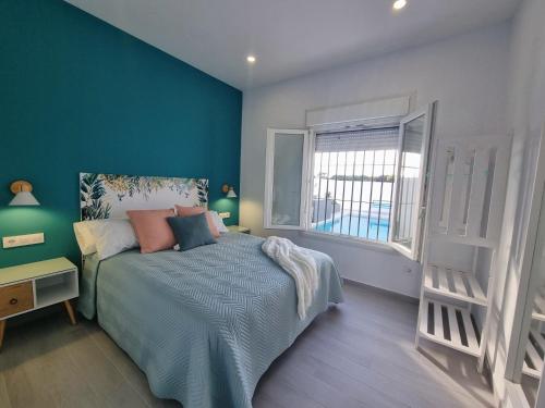 Un dormitorio con una cama con paredes azules y una ventana. en Casa Calma, en Conil de la Frontera