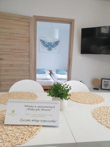 a table with two chairs and a sign on it at Apartamenty Wakacyjne Historie in Międzylesie