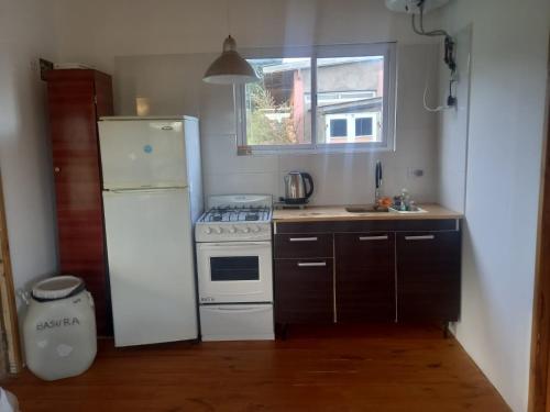 a kitchen with a white refrigerator and a white stove at Cabañas Virazón - Las Dunas in San Eduardo del Mar