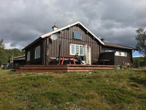 a man sitting on the front porch of a house at Einsetlie by Norgesbooking - cabin by Hallingskarvet in Hovet
