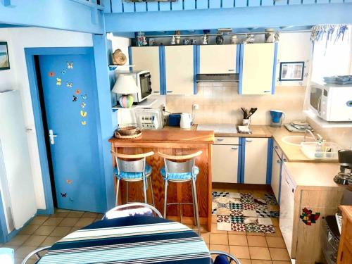 - une petite cuisine avec un comptoir et des tabourets dans l'établissement Petite maison bleue Dune du Pyla 4 personnes 2 vélos, à La Teste-de-Buch