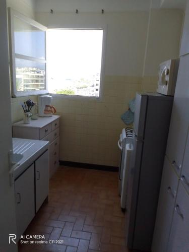 Il comprend une cuisine équipée d'un réfrigérateur, d'un évier et d'une fenêtre. dans l'établissement Bel appartement face mer, à Juan-les-Pins