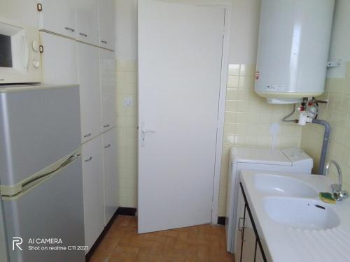 Il comprend une petite cuisine blanche avec un évier et un four micro-ondes. dans l'établissement Bel appartement face mer, à Juan-les-Pins