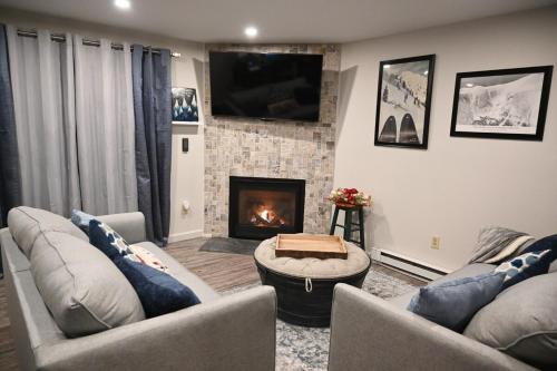 a living room with two couches and a fireplace at Cozy Ski Condo in Waterville Valley