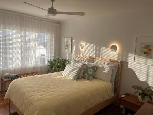 a bedroom with a bed with white sheets and a ceiling fan at The City Cottage in Auckland