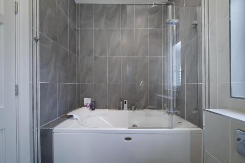 a bath tub in a bathroom with a shower at Waterstone, Narin Portnoo in Portnoo