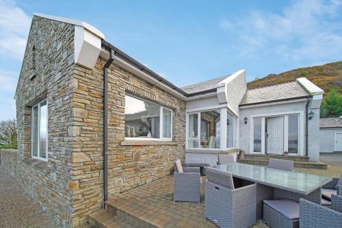 a stone house with a table and chairs on a patio at Waterstone, Narin Portnoo in Portnoo