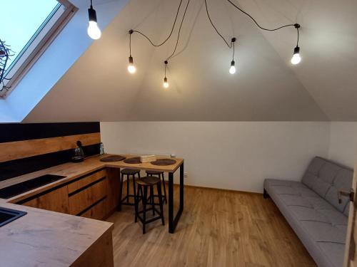 an attic kitchen with a table and a couch at Apartamenty Wakacyjne Historie in Międzylesie