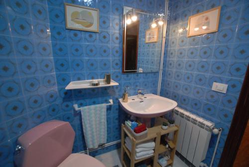 a blue tiled bathroom with a sink and a toilet at M O A Apartamento mariñeiro in Baiona