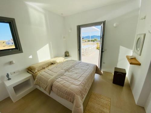 a white bedroom with a bed and a window at Dreamy Sunset Villa a few steps from the Beach in Pounda