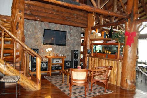 een woonkamer met een televisie en een tafel en stoelen bij Hosteria Los Canelos in El Calafate