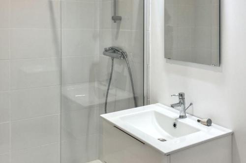 une salle de bain blanche avec une douche et un lavabo dans l'établissement Appartement charmant à Quiberon, 45 m², vue sur jardin, à Quiberon