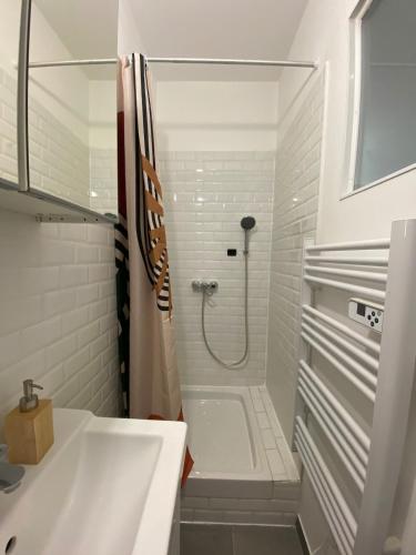 une salle de bain blanche avec une douche et un lavabo dans l'établissement Appartement proche du port, à Toulon