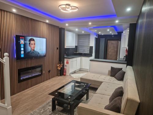 a living room with a couch and a tv on a wall at Uniq 3 Bedroom House in central Watford ,15min to London Euston , close to Harry Potter in Watford