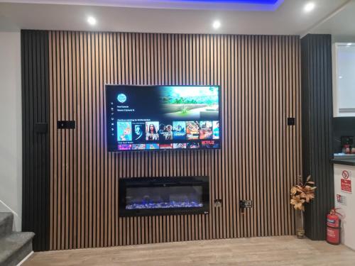a flat screen tv on a wall with a fireplace at Uniq 3 Bedroom House in central Watford ,15min to London Euston , close to Harry Potter in Watford