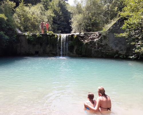 a woman and child sitting in a pool with a waterfall at Fattoria di Arsicci in Caprile