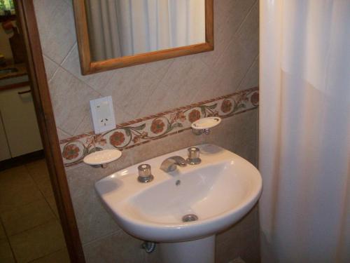 ein weißes Waschbecken in einem Badezimmer mit einem Spiegel in der Unterkunft La casita de Loly in Carilo