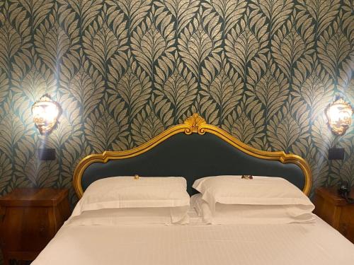 a bedroom with a bed with white sheets and a wallpaper at Pensione Accademia - Villa Maravege in Venice