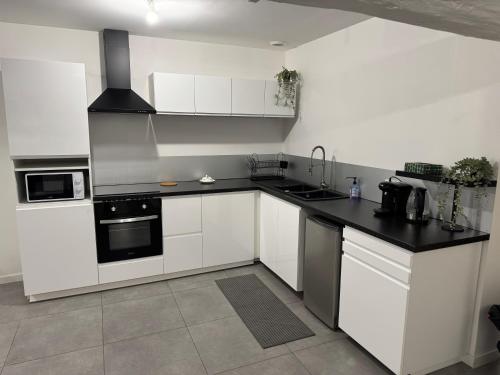 une cuisine avec des armoires blanches et un comptoir noir dans l'établissement T3 10 min de aeroport St exupery plein centre ville, à La Verpillière