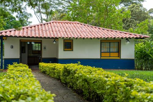 a small blue and white house with a red roof at Hotel Barranqueros Soledén in Armenia