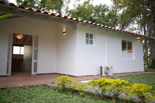 a white house with a porch and a yard at Hotel Barranqueros Soledén in Armenia