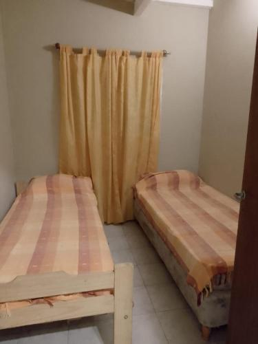 two beds in a room with a curtain at Barrancas de Baradero casa 2 in Baradero