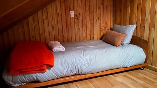 Cama pequeña en habitación con paredes de madera en Cascadas del Llaima, en Refugio Llaima
