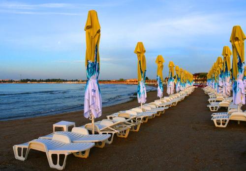 a row of lounge chairs with umbrellas on a beach at Hotel Sanda in Venus