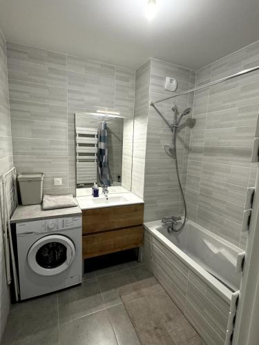une salle de bain avec un lave-linge et une baignoire dans l'établissement Appartement calme et lumineux avec 2 chambres et un parking, à Saint-Ouen