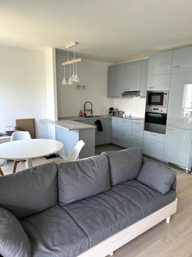 un salon avec un canapé et une table dans une cuisine dans l'établissement Appartement calme et lumineux avec 2 chambres et un parking, à Saint-Ouen