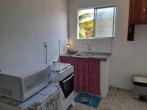 a small kitchen with a microwave and a sink at suite Nata Hospeda in Porto Seguro