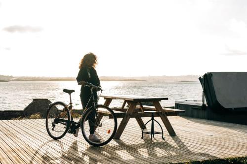 a woman standing next to a bike next to a picnic table at Le Chantier d 'Ernest- Loft T4 les pieds dans l' eau in Carantec