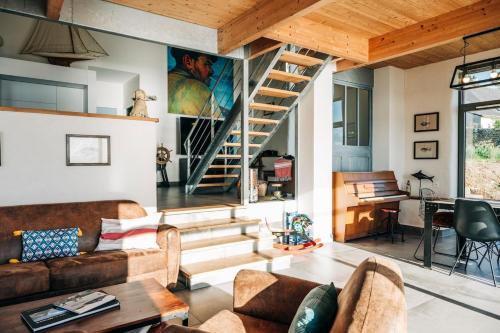 a living room with a couch and a staircase at Le Chantier d 'Ernest- Loft T4 les pieds dans l' eau in Carantec