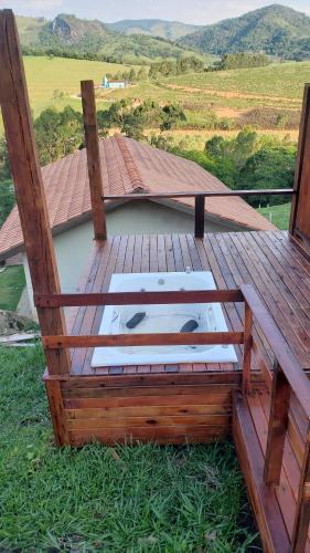 a wooden deck with a table on the grass at Chale bela vista paraisopolis mg in Paraisópolis