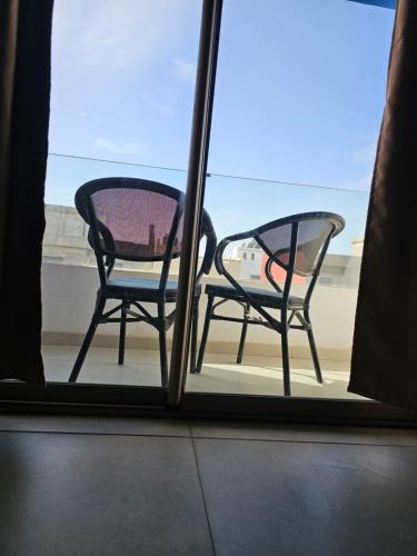 two chairs sitting on a porch looking out a window at Appartement Résidence F3 in Essaouira