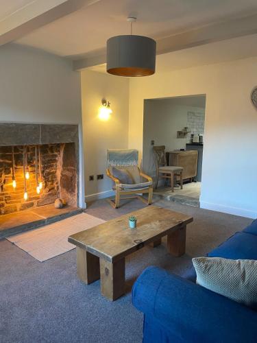 a living room with a table and a fireplace at Willden Cottage in Holmfirth